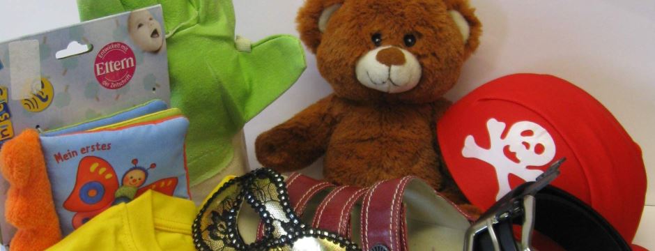 Spielzeug: brauner Teddybär, rote Schirmmütze mit weißem Totenkopf und allerlei anderes