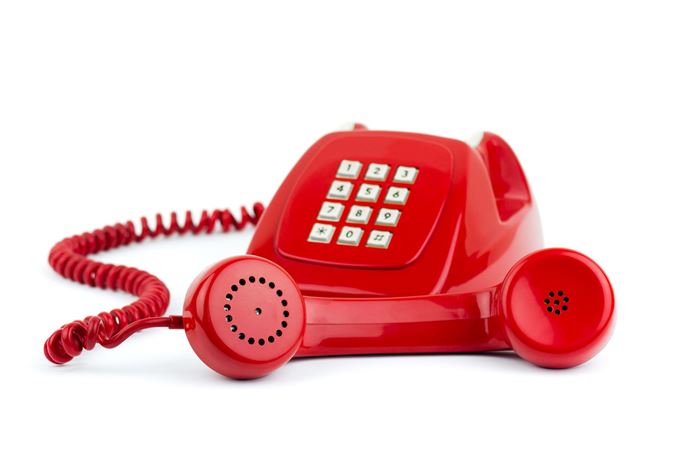 Altertümliches rotes Tastentelefon mit Knochenhörer und weißen Wähltasten und rotem Kabel