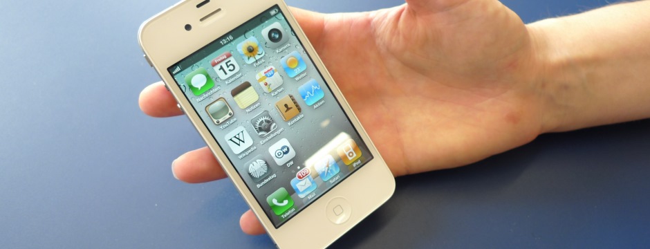 schlanke Hand hält ein älteres Smartphone mit einigen Apps zu sehen in der Hand
