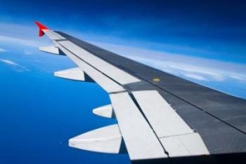 Ausblick aus Flugzeug mit Tragfläche aus großer Höhe mit blauem Hintergrund