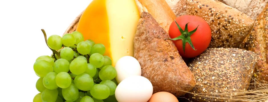 weiße Trauben, Hartkäse, Eier, Körnerbrötchen und Tomate liegen auf einem Haufen