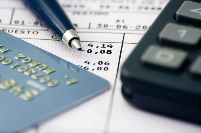Teilansicht / Nahaufnahme einer Zahlentabelle mit Kreditkarte, Taschenrechner und Kugelschreiber