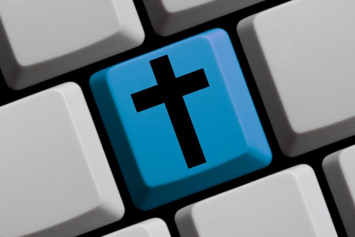 Ausschnitt einer grauen Tastatur mit einer blauen Taste mit schwarzem Kreuz in der MIttel