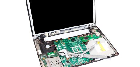 Ein Laptop mit abgenommenem Gehäuse und Tastatur zeigt sein Innenleben, darauf lieben Rohrzange und Rollgabelschlüssel